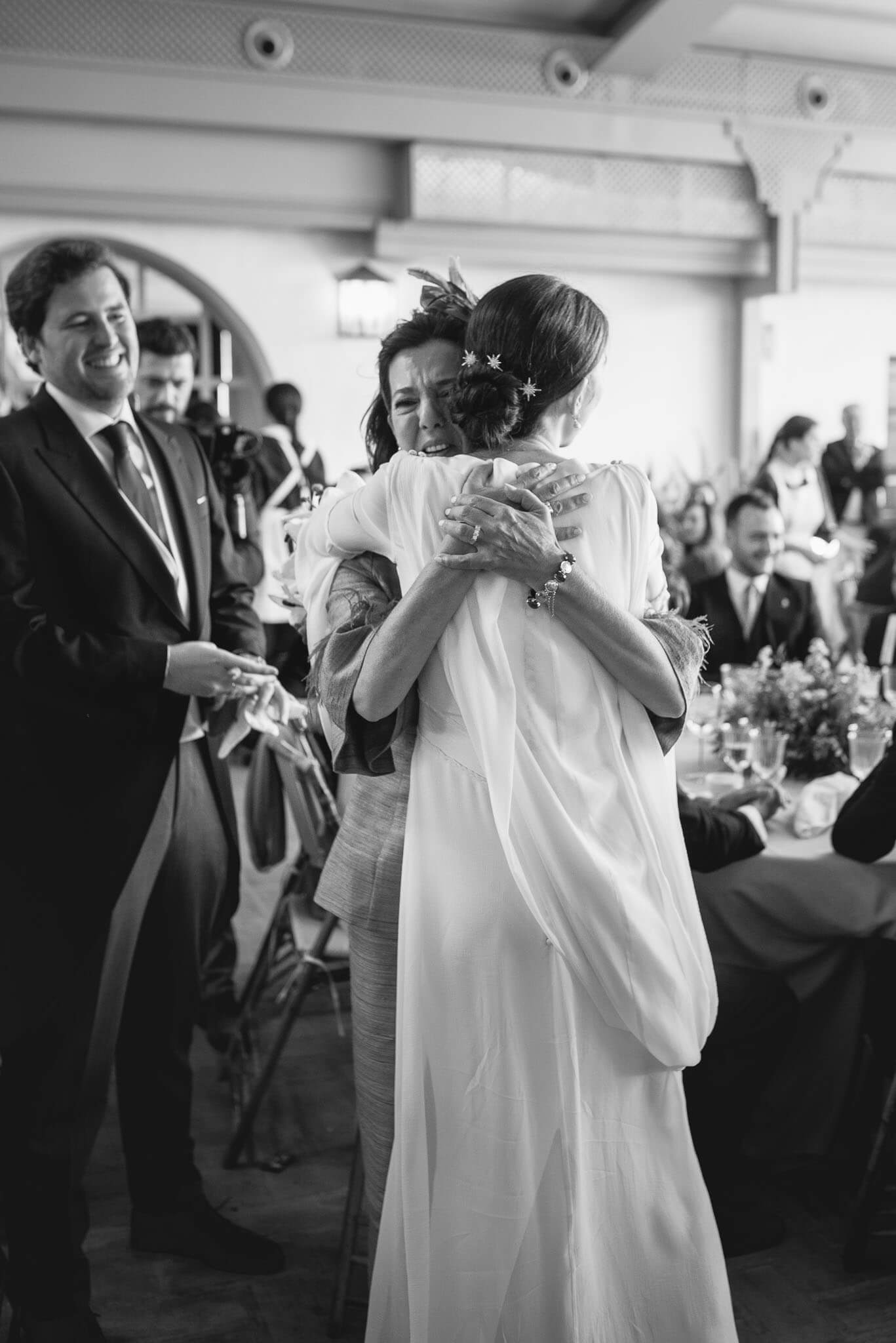 Madre llora mientras abraza a su hija vestida de novia en el convite de la boda (Foto en color)